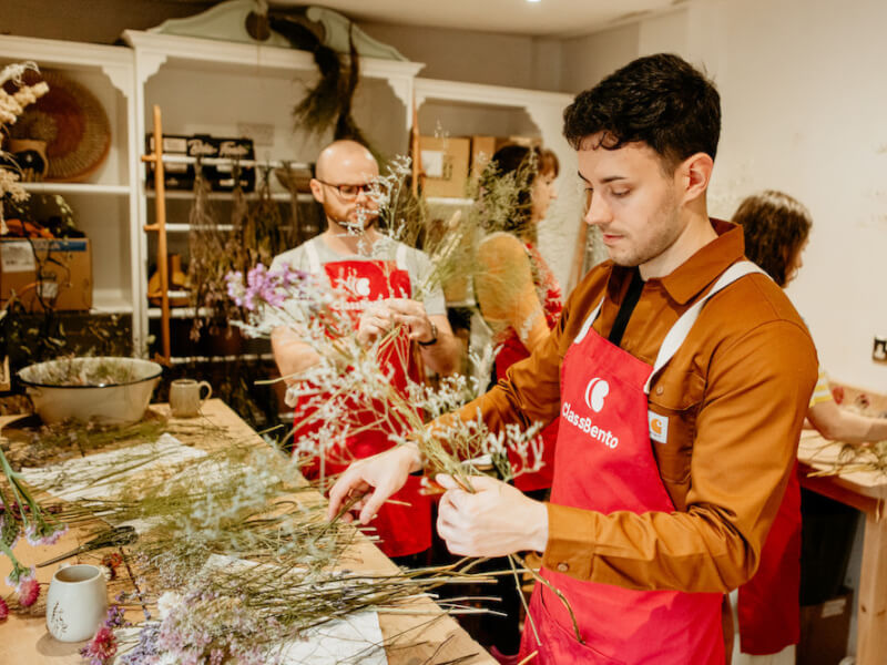 A man arranges a selection of dried flowers